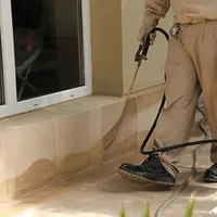 General pest control technician spraying exterior perimeter around a home in Allentown, PA