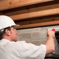 Termite inspection technician checking a basement wall and framing for termite activity in Allentown, PA