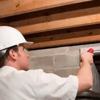Termite inspection technician checking a basement wall and framing for termite activity in Allentown, PA